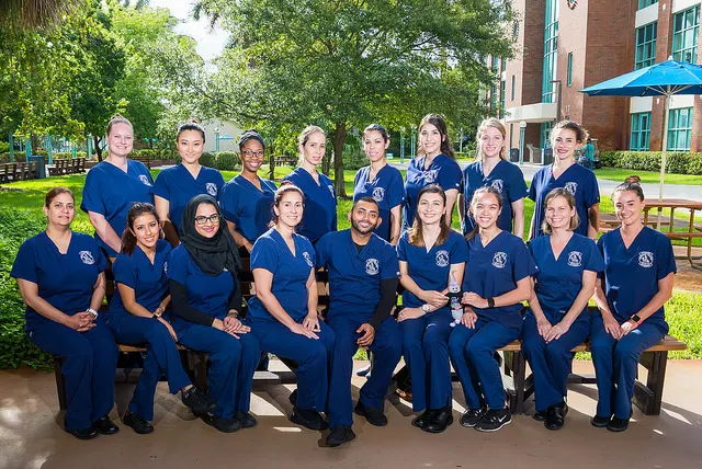 A group of 20 students pose for the camera wearing blue dental hygienists uniforms