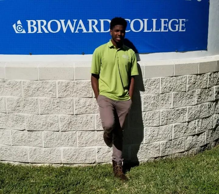 Young African American man stands against a wall posing for the camera